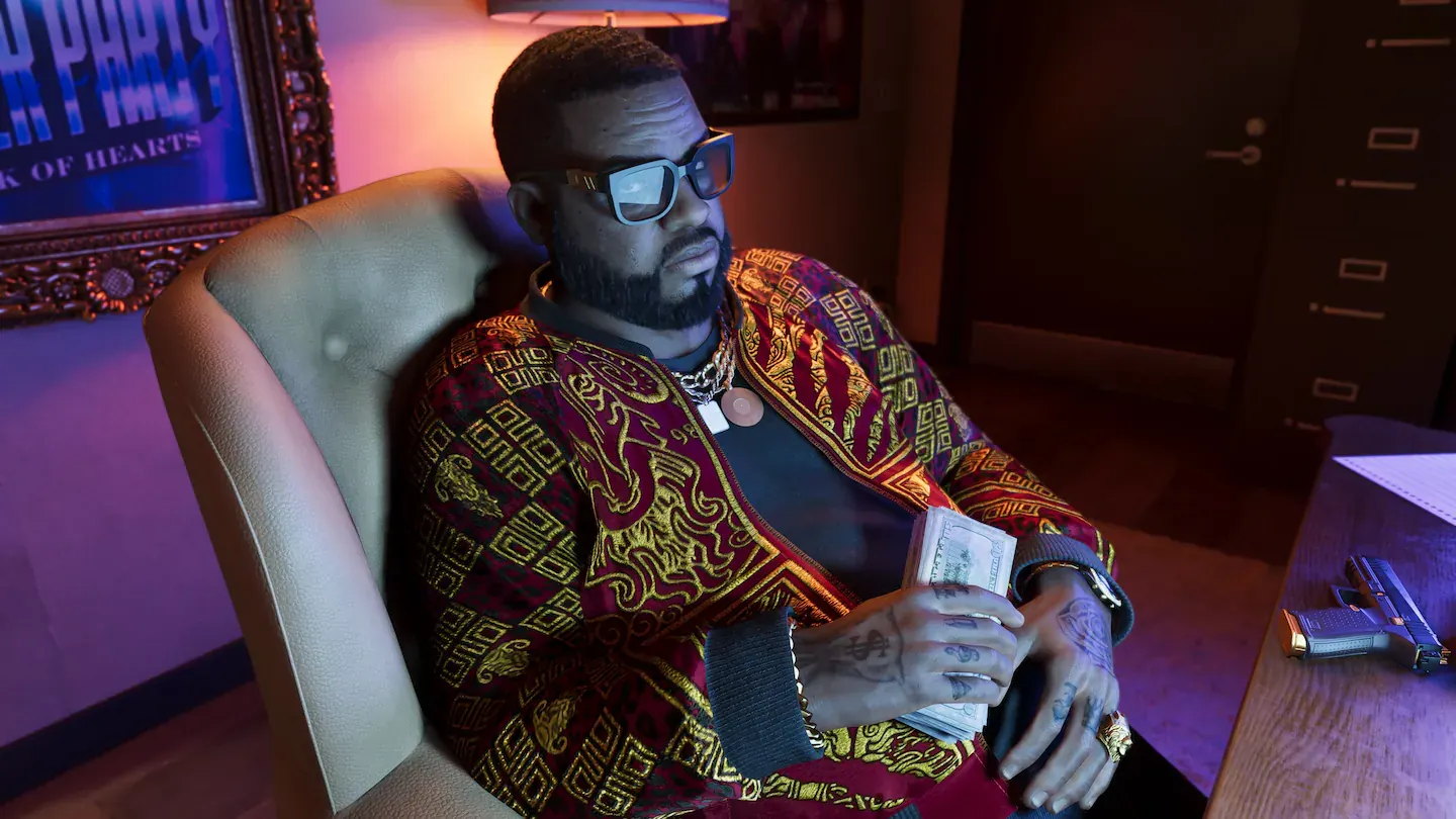 Hombre con gafas de sol, chaqueta estampada en granate y dorado y cadena de oro, sentado en un sillón con un fajo de billetes en la mano. Al fondo, un cartel enmarcado y una pistola sobre la mesa.