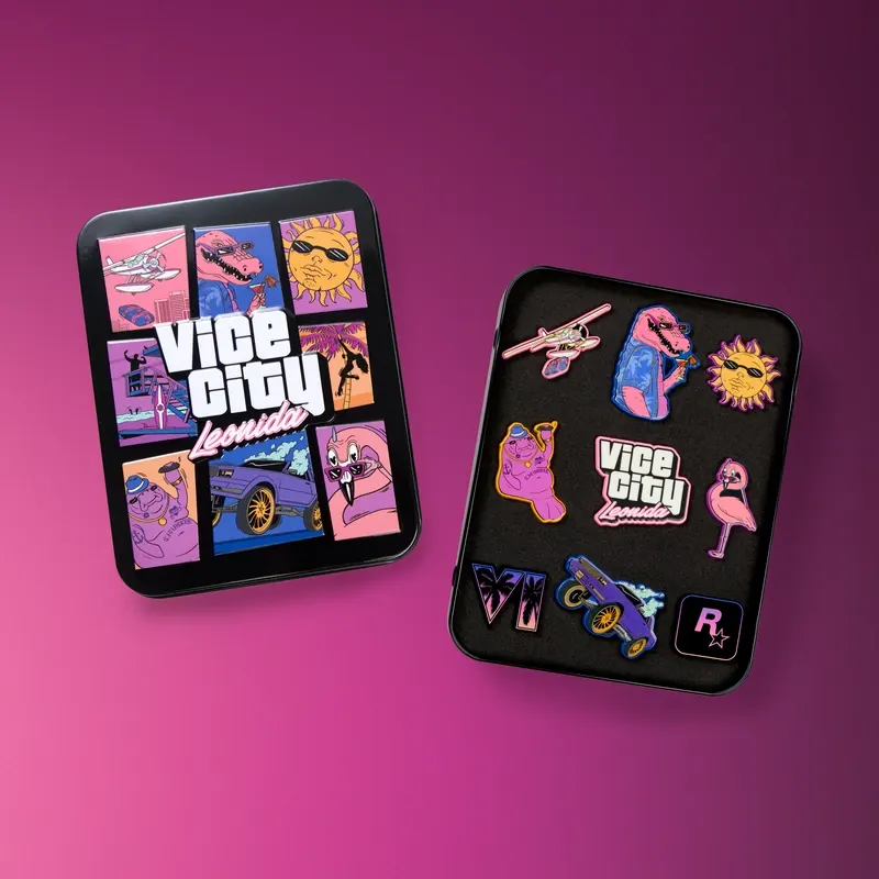 Una lata metálica con la tapa ilustrada con viñetas y el rótulo «Vice City Leonida», y al lado la lata abierta con nueve pines de colores sobre espuma negra.