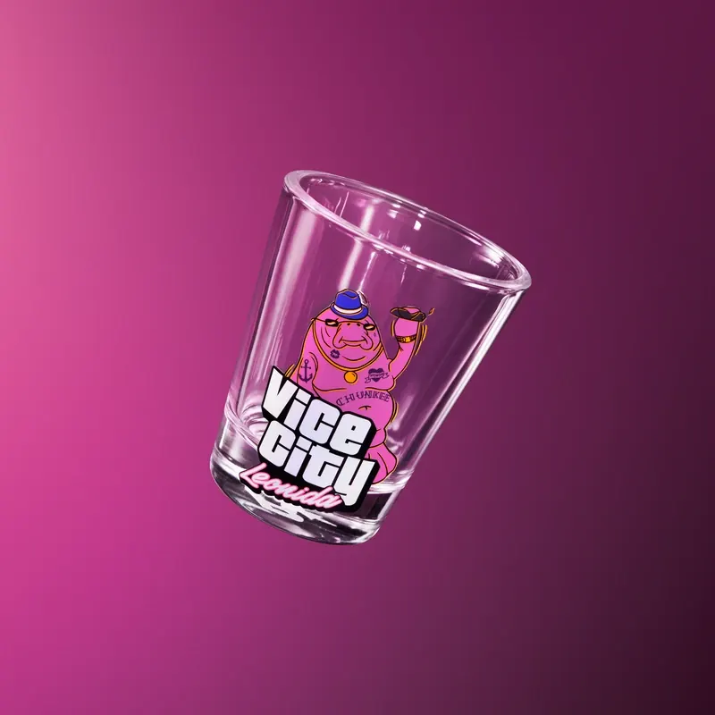 Vaso de chupito de cristal transparente con el dibujo de un manatí morado con sombrero azul y tatuajes, sobre el rótulo «Vice City Leonida».