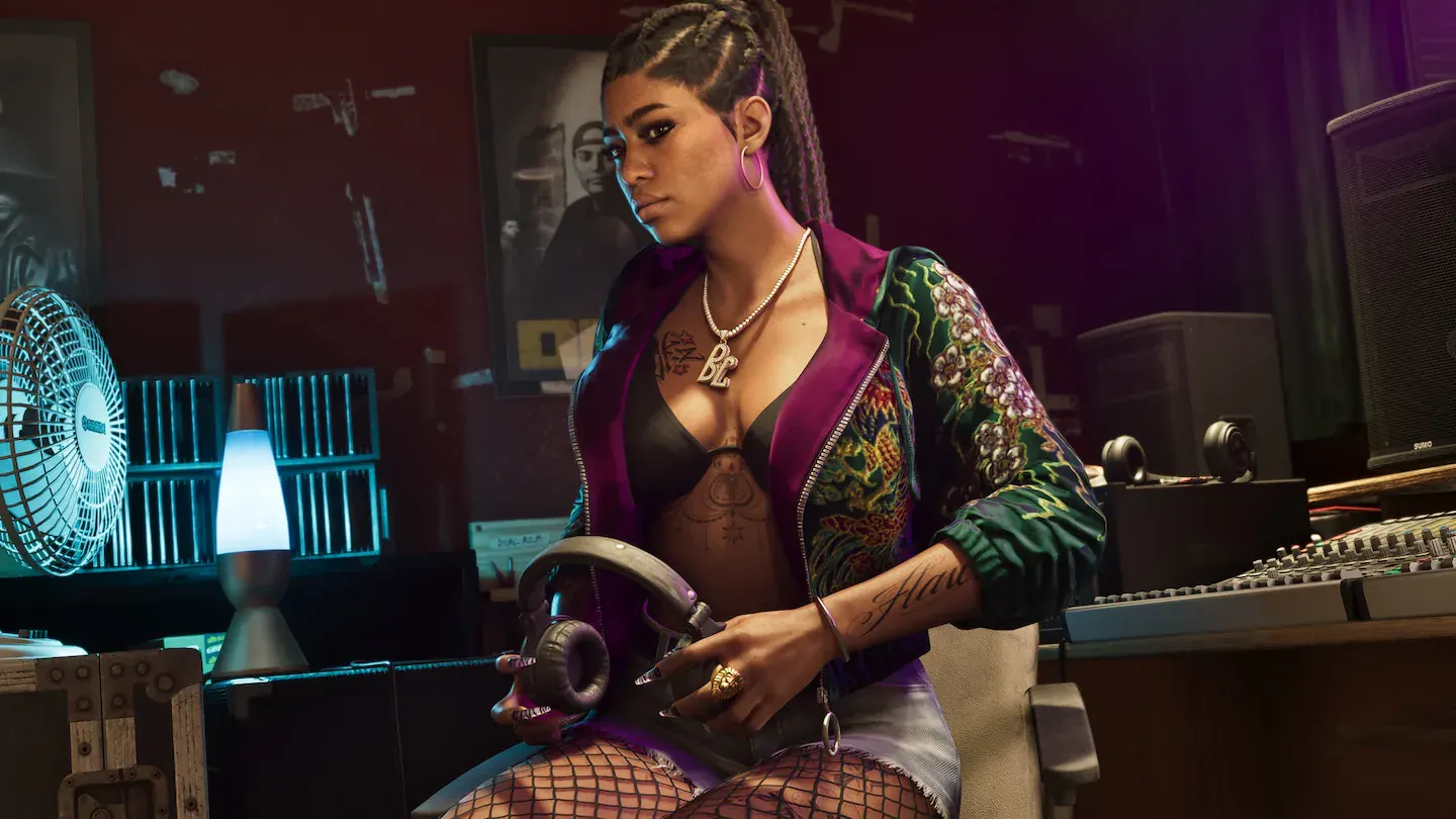 Mujer joven con trenzas y chaqueta bordada, sentada junto a una mesa de mezclas en un estudio de grabación, con unos auriculares en la mano.