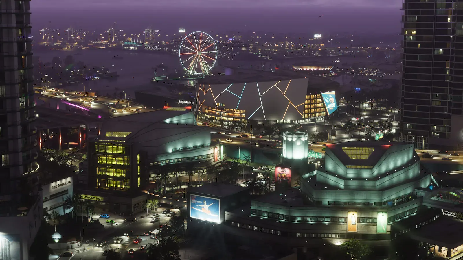 Vista nocturna del centro de Vice City desde un edificio alto: un pabellón iluminado llamado Sahara Arena, una noria, una sala de conciertos, el centro de artes y las grúas del puerto al fondo.