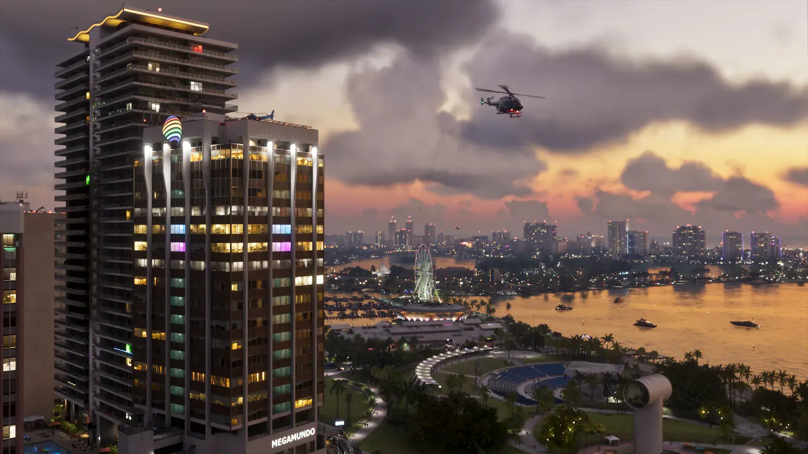 Atardecer sobre la bahía de Vice City. En primer plano, dos torres de apartamentos iluminadas; al fondo, una noria, yates y el perfil de la ciudad encendiéndose. Un helicóptero cruza el cielo anaranjado.